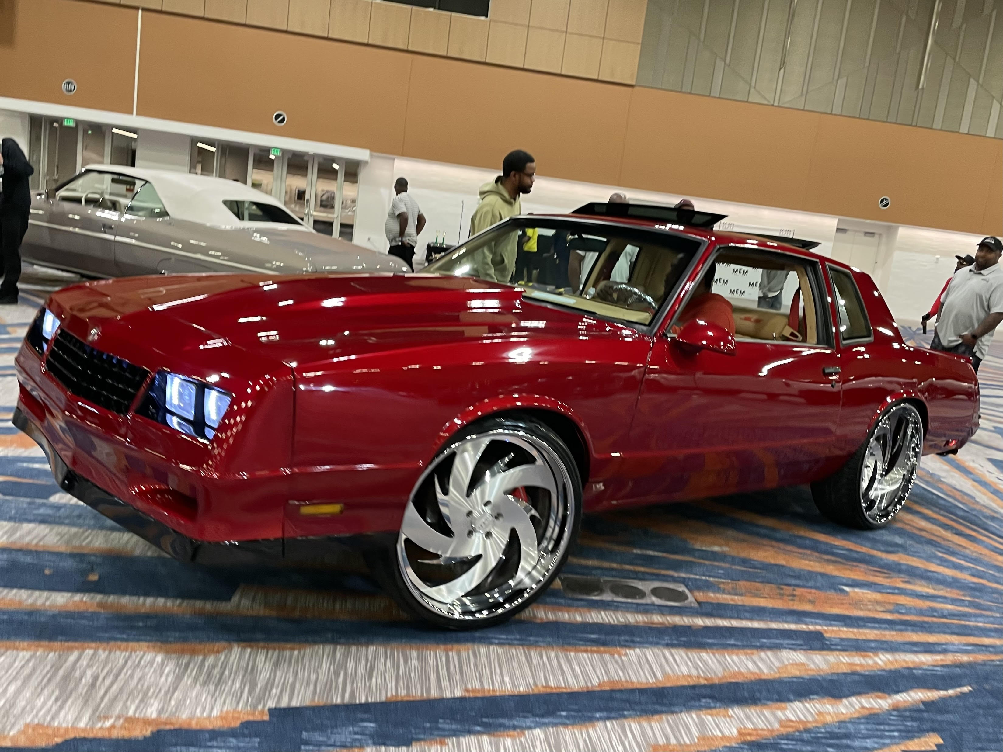 Candy-red classic coupe with oversized wheels indoors